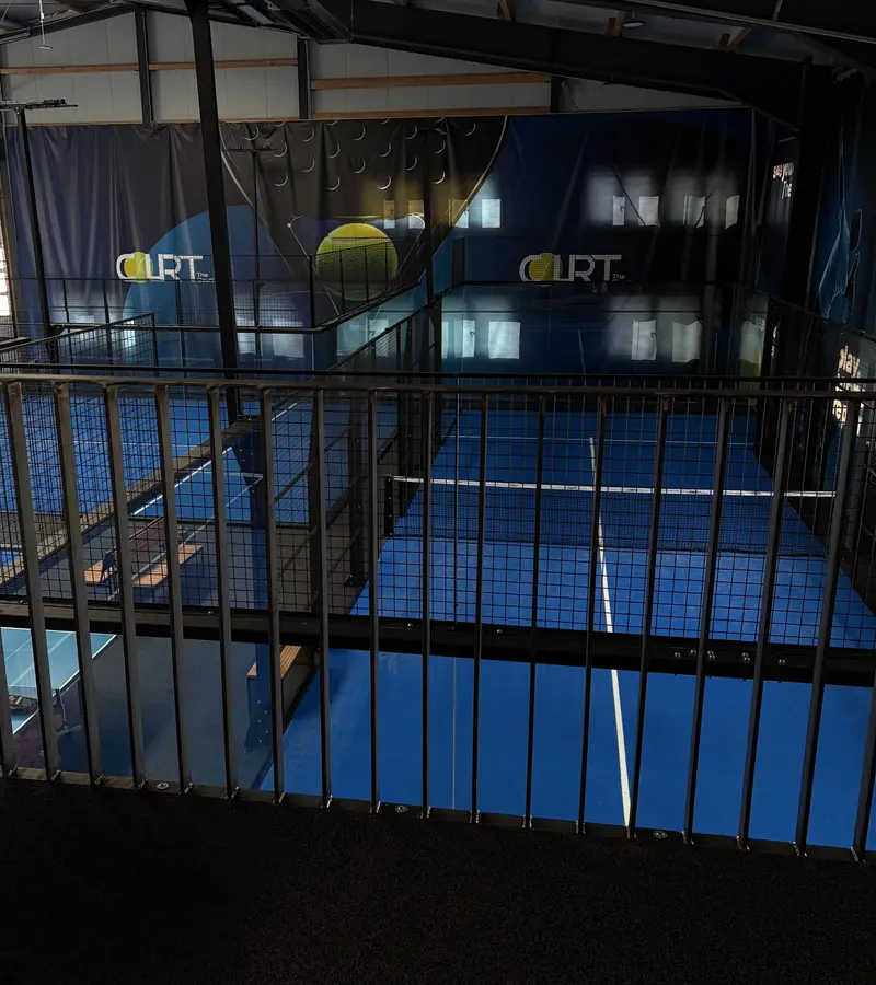 Padel-Court mit Glaswänden und TheCourt-Logo an der Hallenwand.
