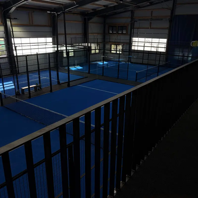 Blick von der Galerie auf die blauen Padel-Courts in der Halle von TheCourt.